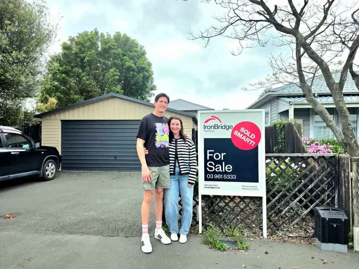 Couple outside their new home with a Sold Smart sign