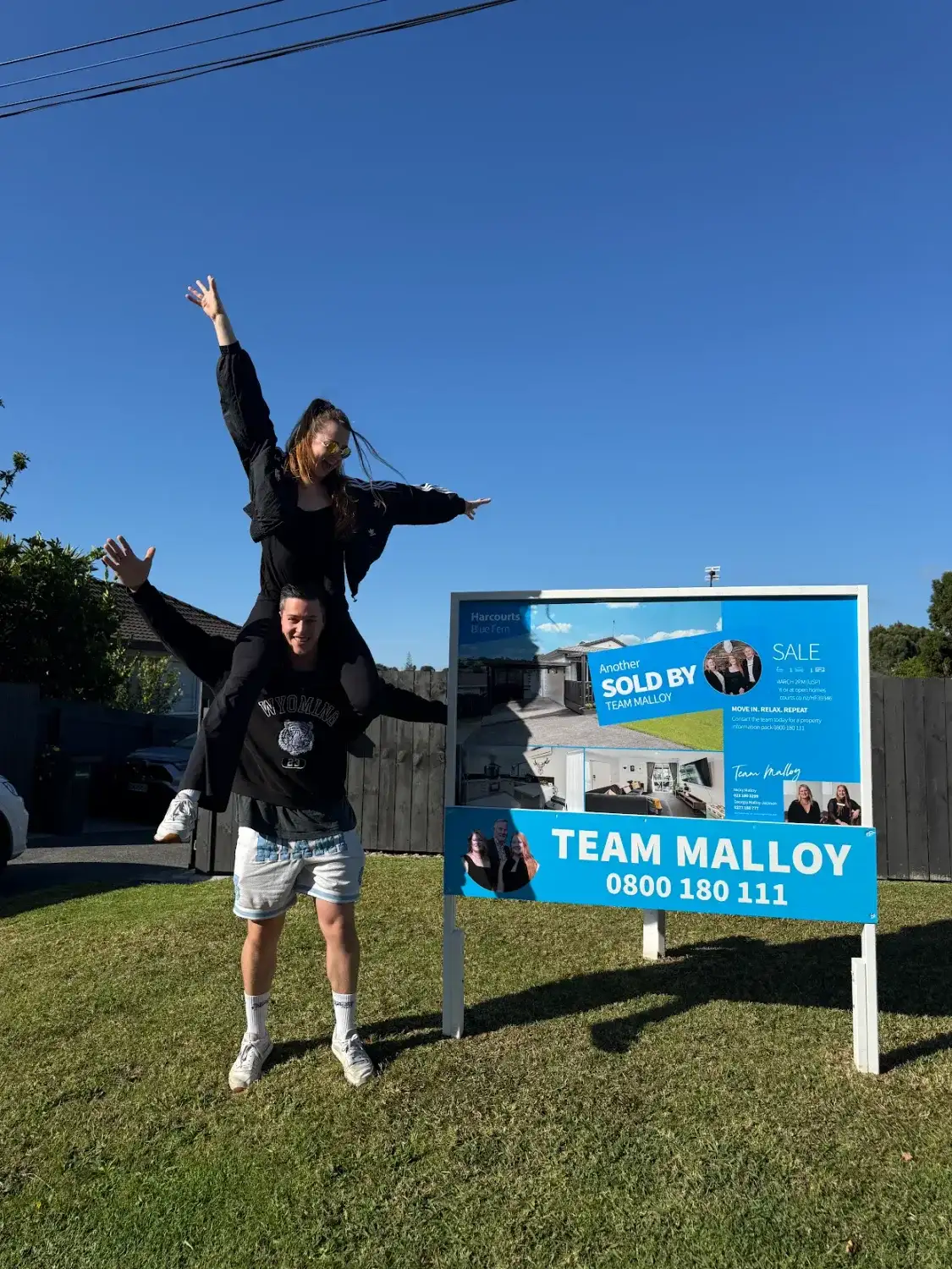 Couple celebrating beside their Sold sign
