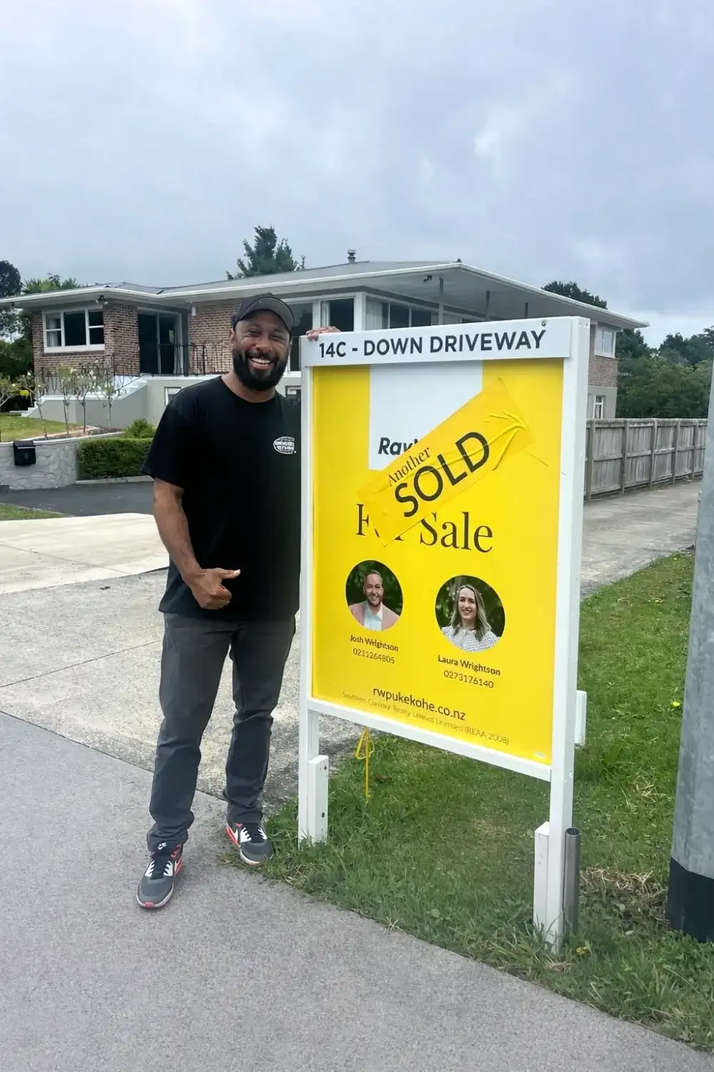New home owner giving a thumbs up beside his Sold sign