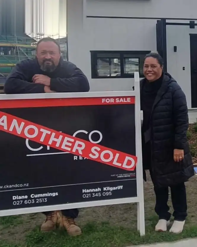 Couple beside their Another Sold sign at a new build