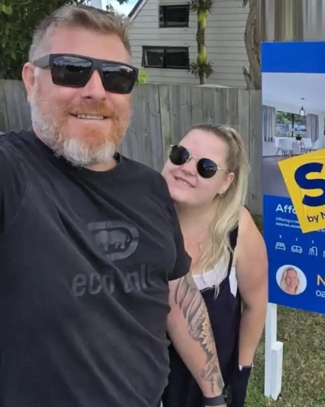Couple taking a selfie beside their Sold sign